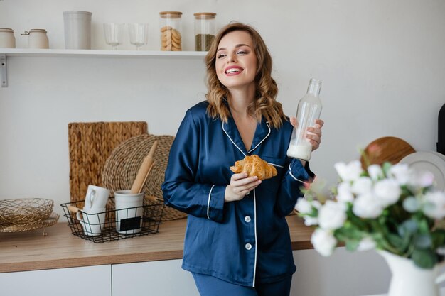 Beautiful girl in pajamas holding a croissant and milk