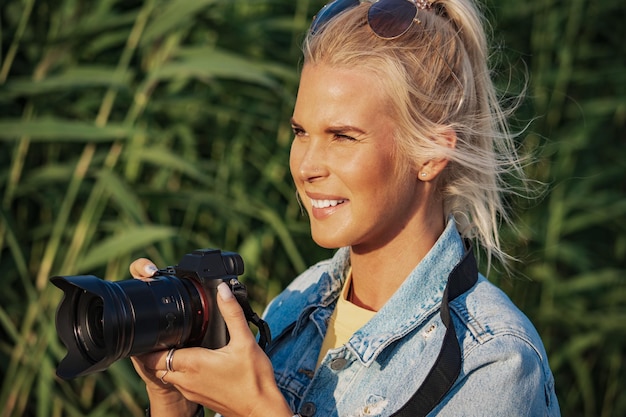 Beautiful girl photographer with a camera in her hands outdoors in summer closeup photo