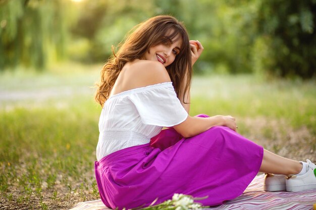 Beautiful girl on a picnic The model sits on the green grass in the park beauty and health