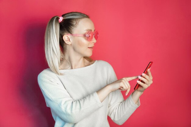 beautiful girl in pink glasses and on a pink background calls on the phone