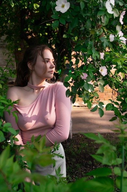 Bella ragazza in un vestito rosa si trova vicino a fiori colorati