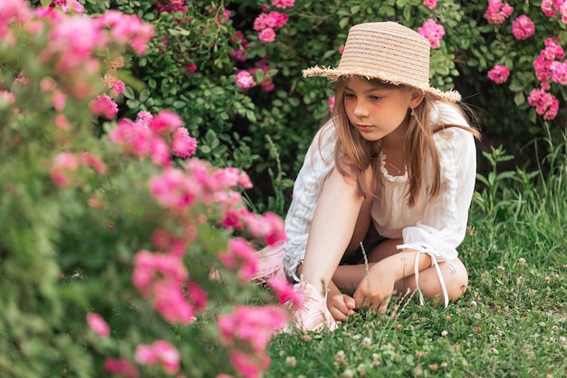 Beautiful girl among pink roses outside