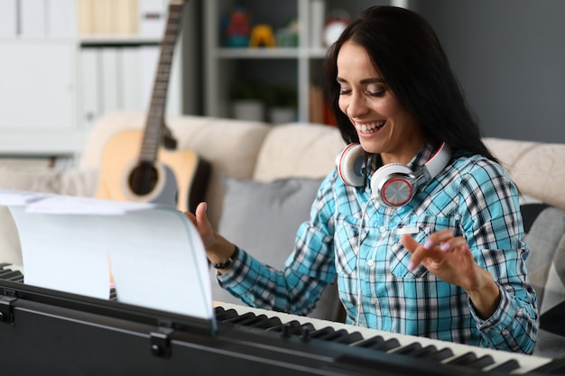 Beautiful girl playing synthesizer at home and laughing