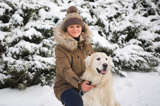 雪の中で彼女の犬と遊ぶ美しい少女