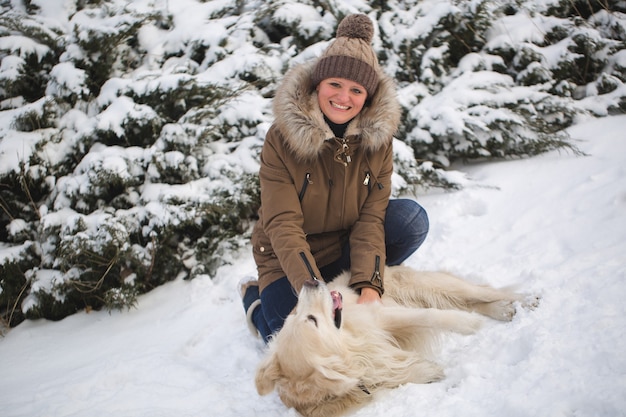 Beautiful girl playing with her dog in the snow