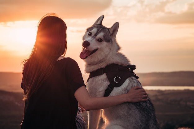 Фото Красивая девушка играет с собакой на закате
