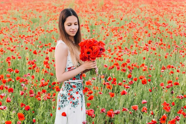 Beautiful girl in a poppy field at sunset concept of freedom