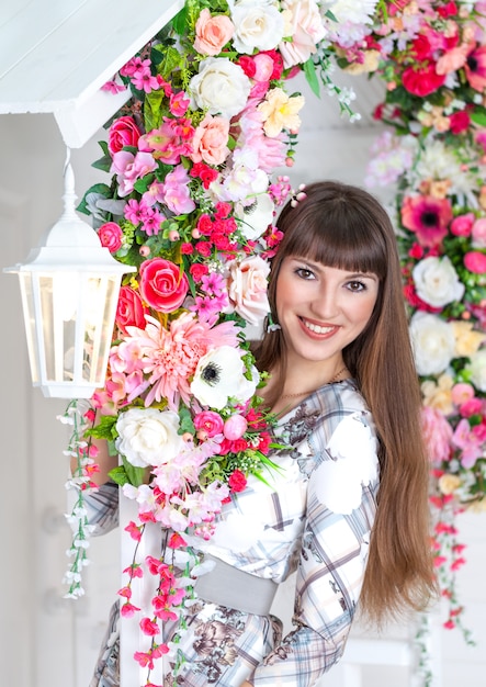 Bella ragazza sotto il portico con lanterna bianca e fiori