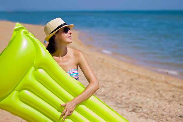 Bellissimo ritratto di ragazza con materasso galleggiante gonfiabile su sfondo estivo spiaggia con spazio copia