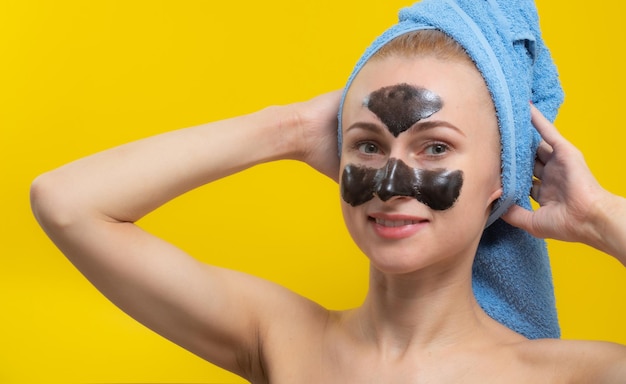 A beautiful girl poses for the camera with a black face mask on a yellow background.