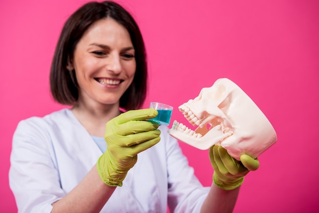 Beautiful girl proposes mouthwash for artificial skull