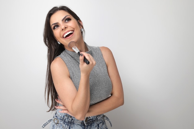 Beautiful girl putting on makeup on white background.