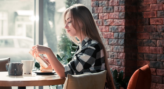 Photo beautiful girl reading a book in a cafe