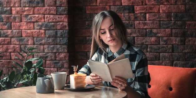 Beautiful girl reading a book in a cafe