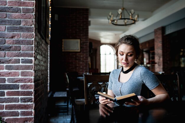 beautiful girl reads an interesting book in a cafe