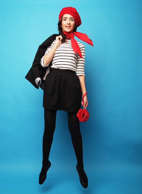 Beautiful girl in a red beret. French style. Over blue background.