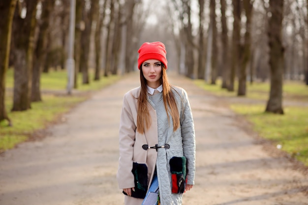Красивая девушка в красной шапочке гуляет по городу