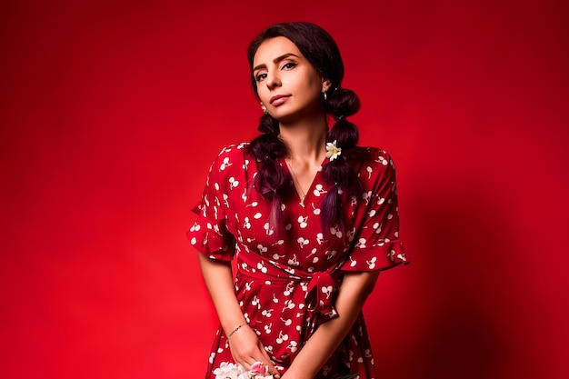 Beautiful girl in a red dress on a red background with flowers