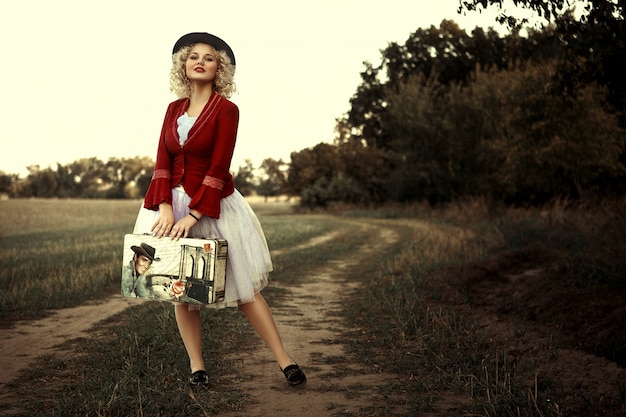 Beautiful girl in a red jacket is posing on the plain air