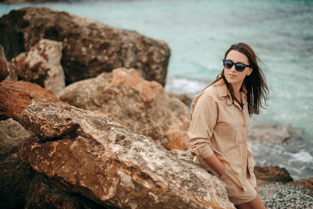 Beautiful girl relaxing and smiling outdoor at summer beach Positive woman in sunglasses enjoying warm weather