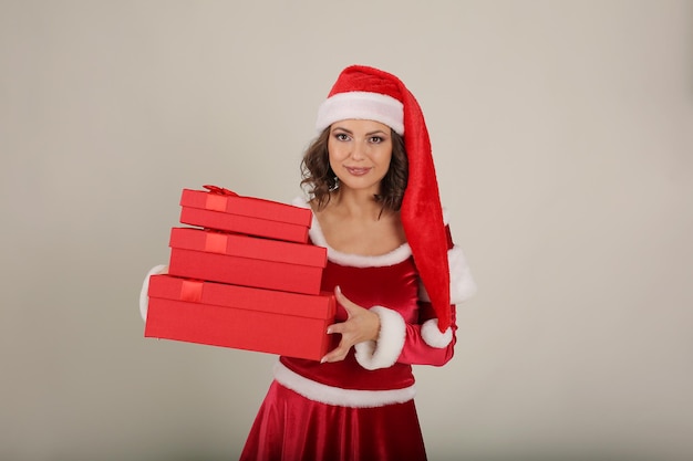 a beautiful girl in a Santa Claus hat and a snow maiden costume holds gift boxes in her hands