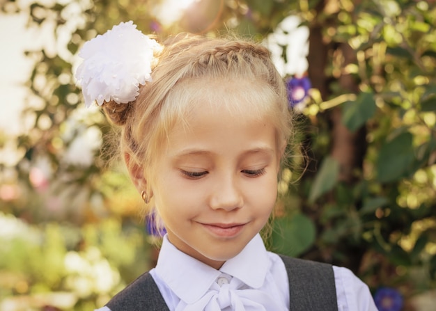 A beautiful girl in school clothes stands with her eyes down