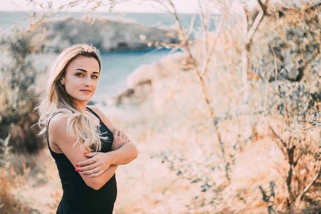 Bella ragazza in pantaloncini e maglietta sullo sfondo del mare e delle rocce in lontananza