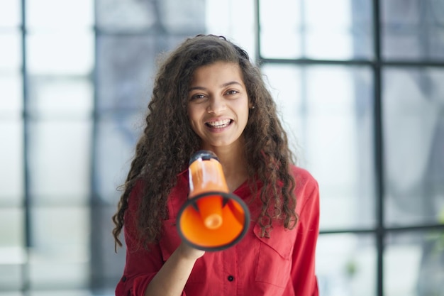 Beautiful girl shouting into a megaphone in a modern office