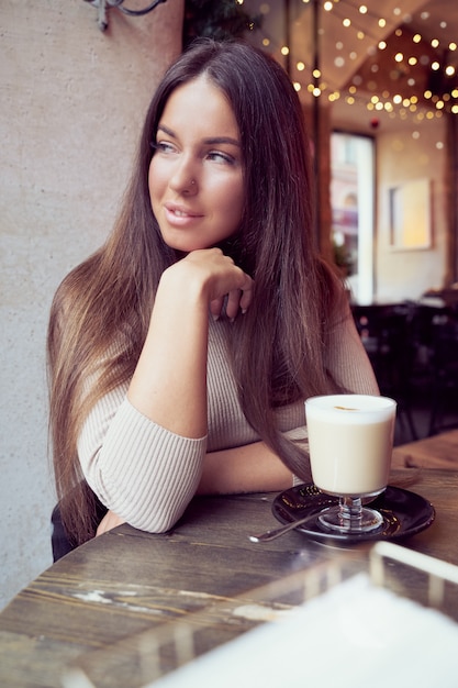 La bella ragazza si siede in un caffè nelle vacanze di natale