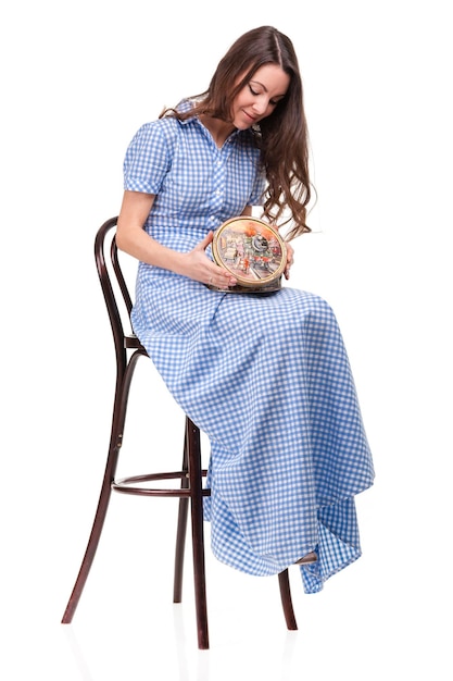 Beautiful girl sits on chair with box of chocolates in hands against white background