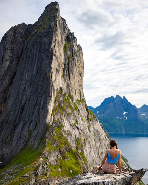 아름다운 소녀는 노르웨이의 유명한 세글라 산, 센자(senja)의 전망을 즐기는 바위 위에 앉아 있다
