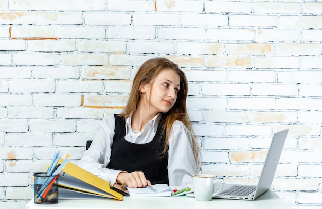 A beautiful girl sittin behind of the desk and working High quality photo