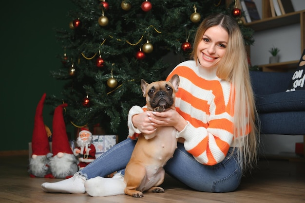 Beautiful girl sitting on the couch with a dog on the background of Christmas