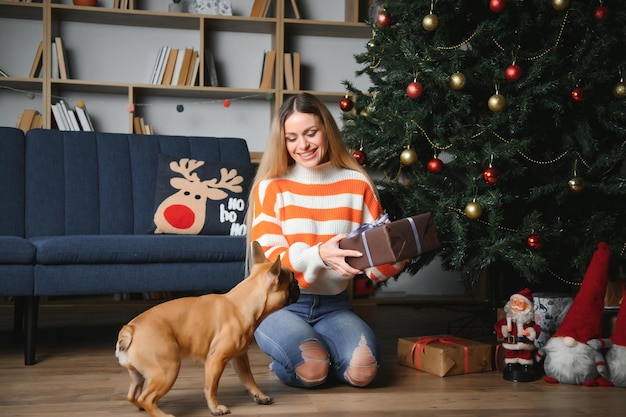 Beautiful girl sitting on the couch with a dog on the background of Christmas