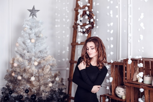 Bella ragazza seduta vicino all'albero di natale