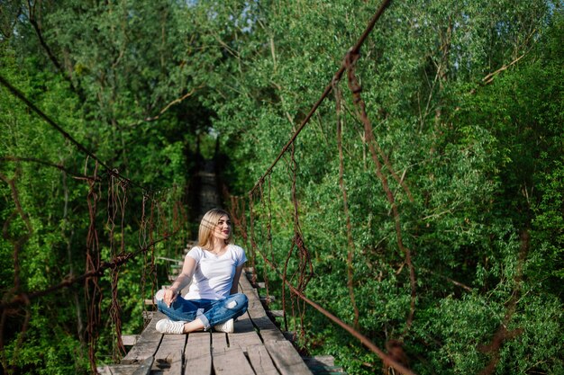 Beautiful Girl sitting on old wooden bridge.weekend and Vacation in the summer park.