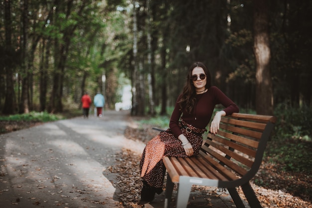 Beautiful girl sitting in the Park on a bench in autumn