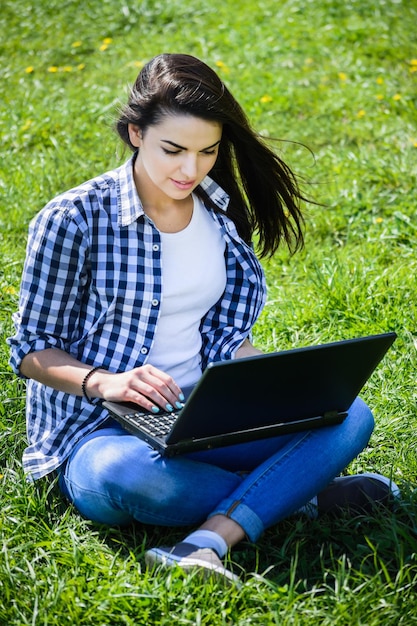 Beautiful girl sitting in the park with a laptop