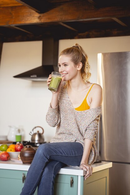 彼女のおいしい飲み物を楽しみながらテーブルに座っている美しい少女