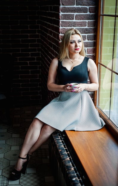 beautiful girl sitting on the windowsill near the window with a cup of coffee, noise