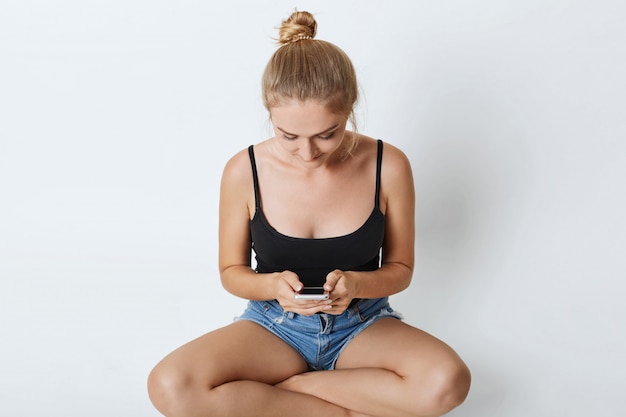 beautiful girl sitting with crossed legs typing on mobile phone