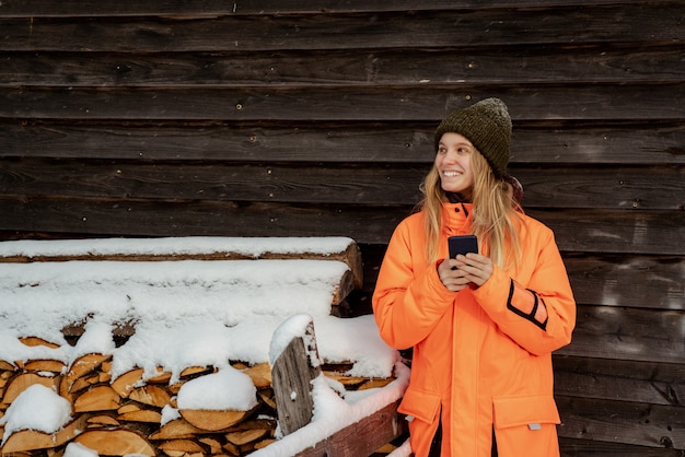 사진 아름 다운 소녀 미소 스노 손에 휴대 전화와 함께 혼자 서. 산 야외, 겨울 스포츠 활동.