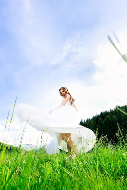 하얀 드레스를 입고 웃고 있는 아름다운 소녀가 풀밭을 산책하며 즐겁게 춤을 춥니다