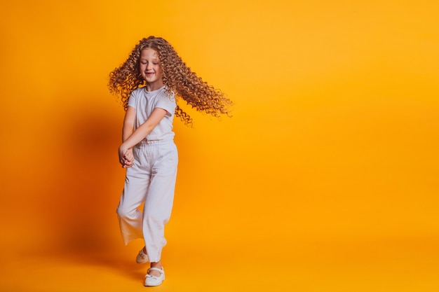 beautiful girl spinning in white tshirt on yellow background in studio