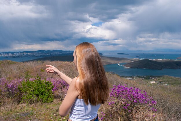 ピンクの花Rhododndronと春の牧草地の美しい少女