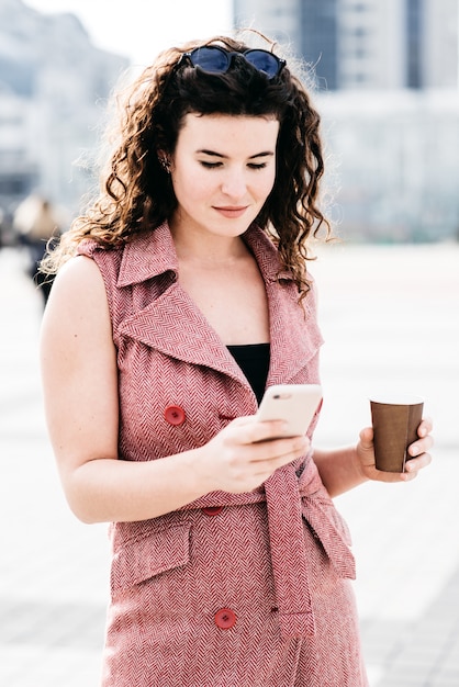 Bella ragazza in piedi con il caffè sulla strada