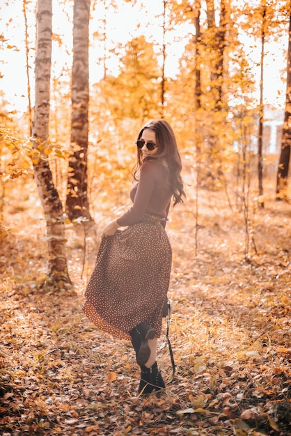 Beautiful girl stands in the background in autumn foliage in the Park