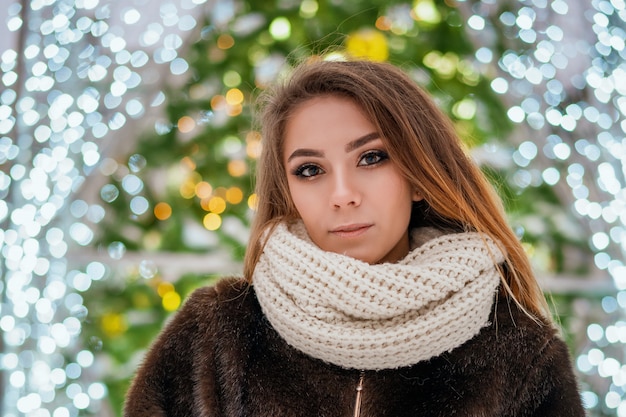 A beautiful girl stands on the background of the city Christmas tree