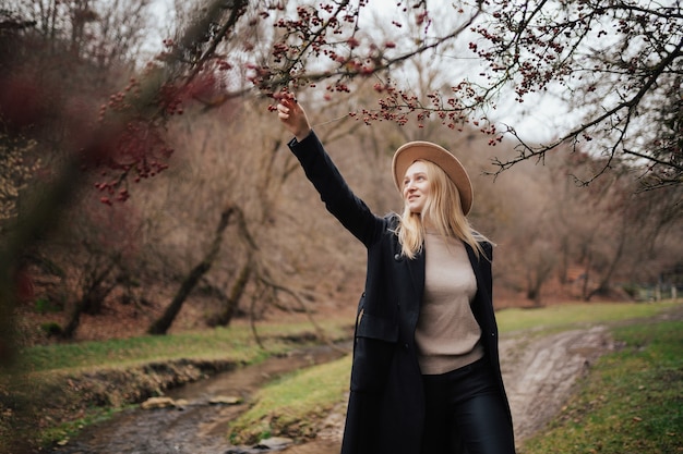 A beautiful girl stands on the background of a tree with red berries.