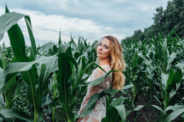 Beautiful girl stands in the field of young corn. Agriculture.